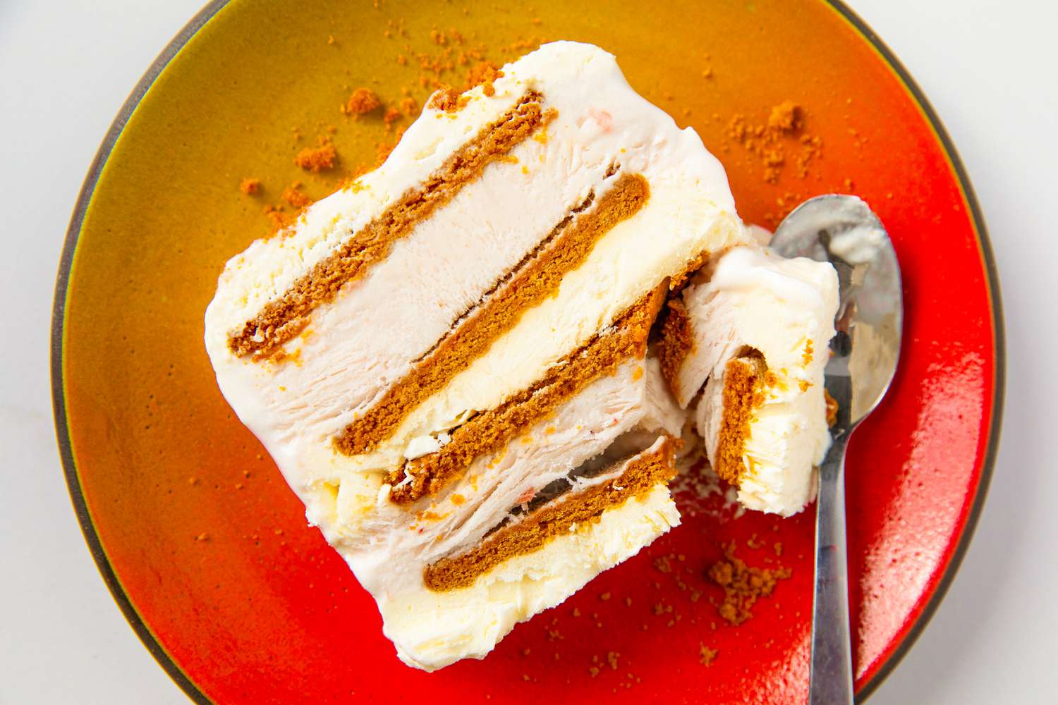A slice of ice cream cake layered with cookies on a plate with a spoon