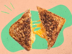 A grilled cheese sandwich cut in half with melted cheese stretching between the halves