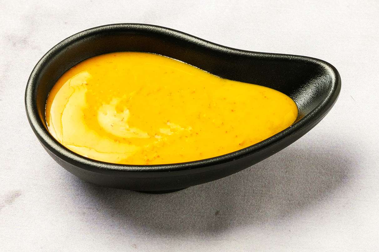 Small black dish containing a smooth, yellow sauce