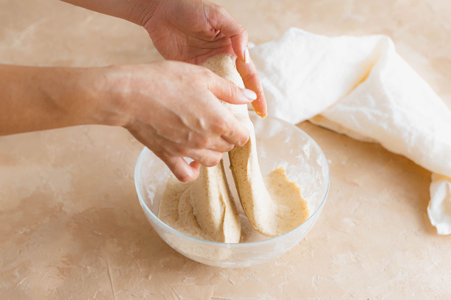 Lifting the sourdough started with two hands to make spiced sourdough bread shaped like a pumpkin.