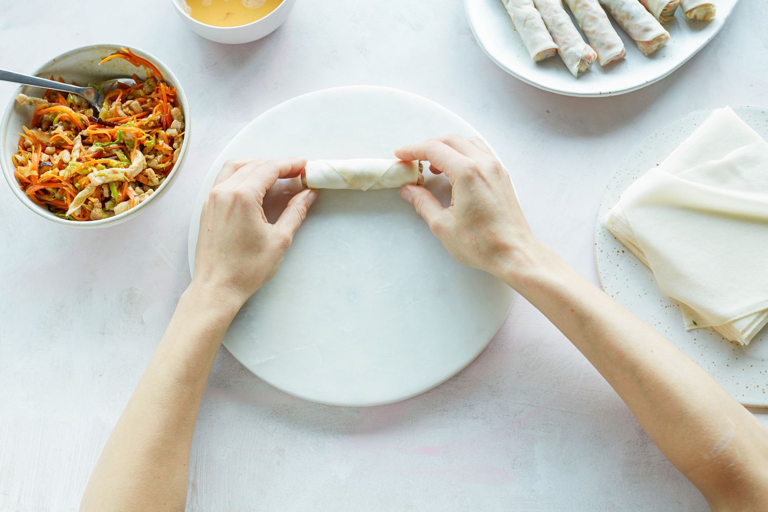 Hands showing how to roll a spring roll.