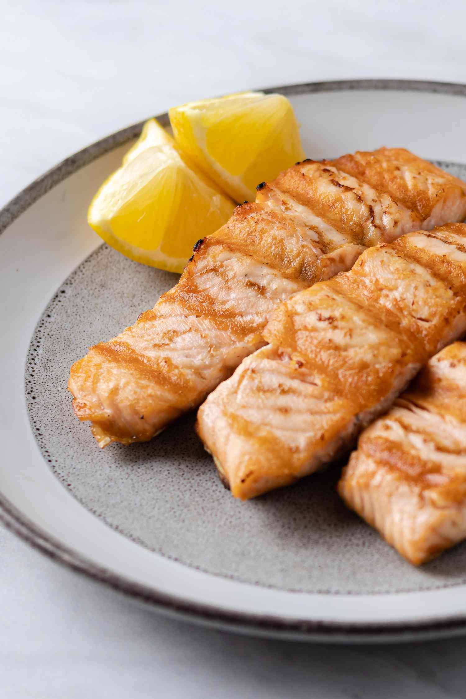 A plate of grilled salmon with lemon wedges on the side