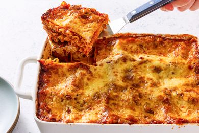 A dish of baked lasagna with a portion being lifted out using a spatula
