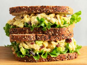 Triplelayered sandwich made with seeded bread lettuce and a creamy filling placed on a wooden surface