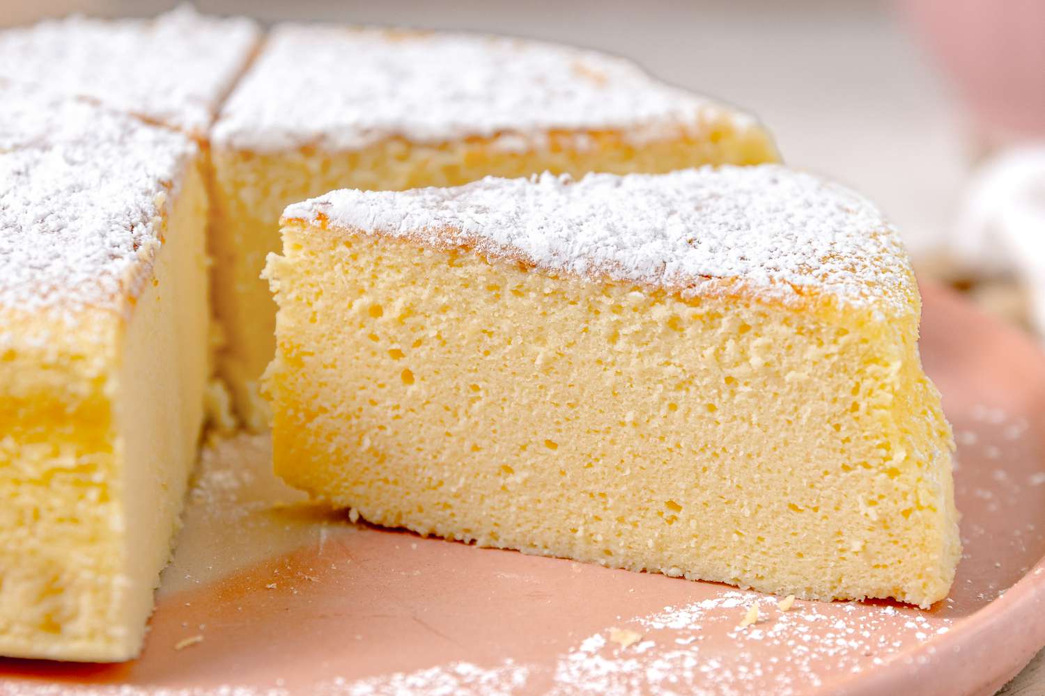 Slice of Japanese Cheesecake Resting on a Plate With the Rest of the Cheesecake 