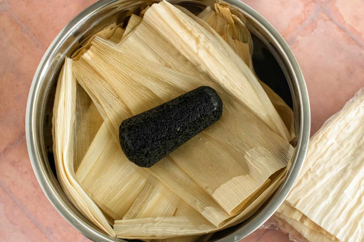 Corn Husks in a Bowl of Warm Water and Held Down with a Tejolote