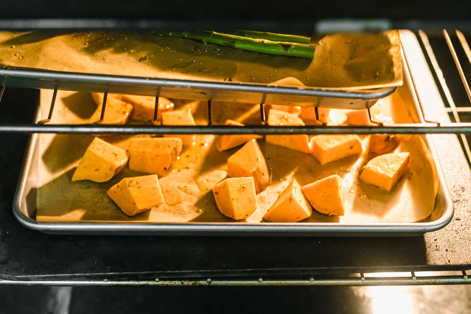 Sweet potatoes on a sheet pan roasting in the oven