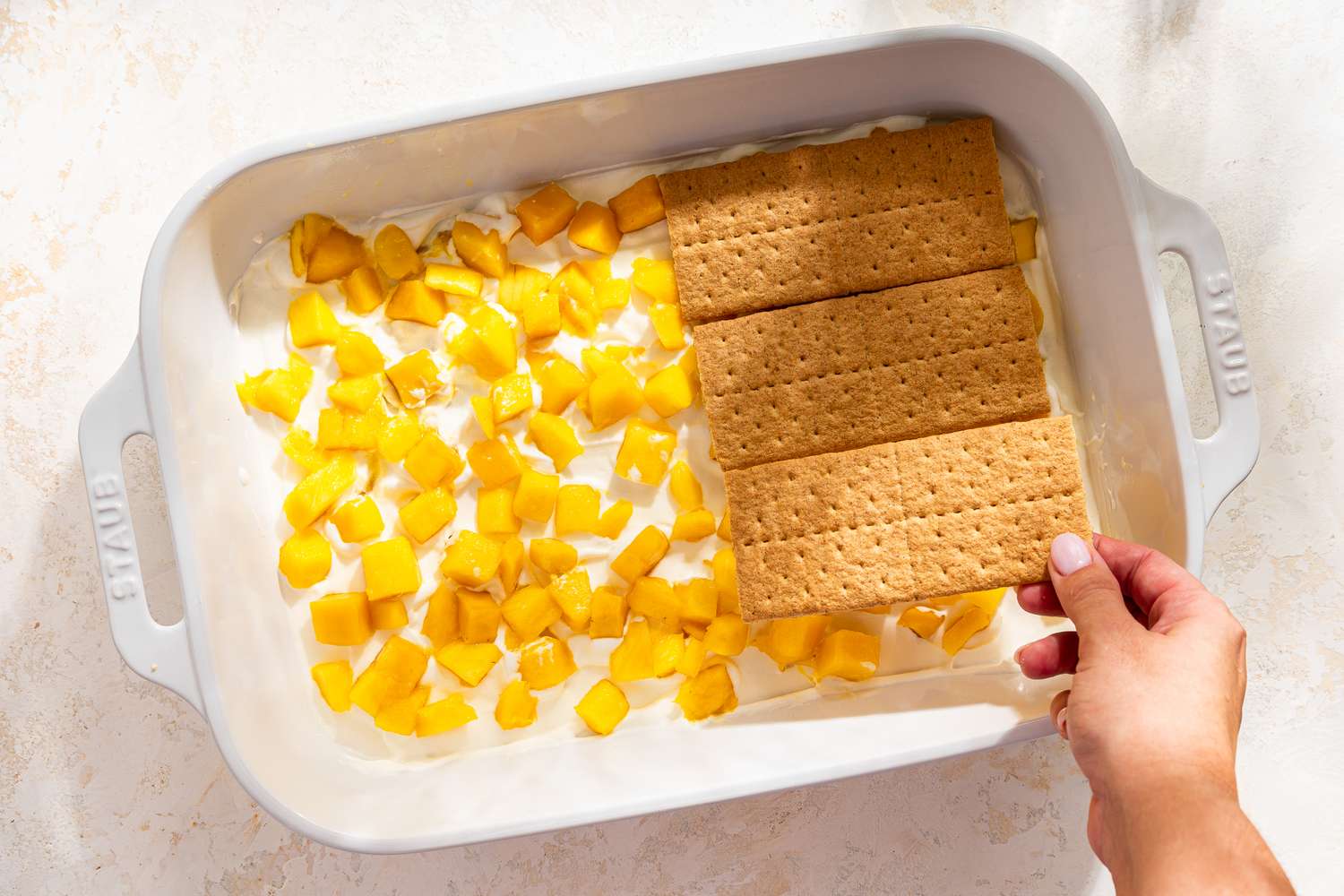 graham cracker layer added on top of the mango pieces in the dish for mango float recipe