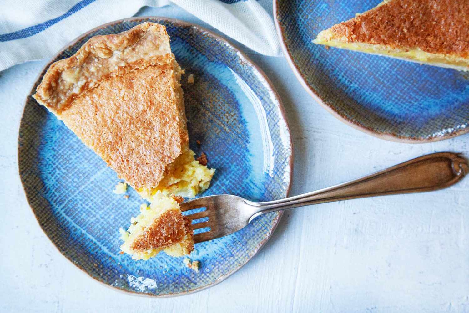 Homemade chess pie on a plate with a forkful of the pie.