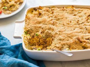 Angle view of a white baking dish of chicken tetrazzini with a slice removed next to a blue cloth napkin