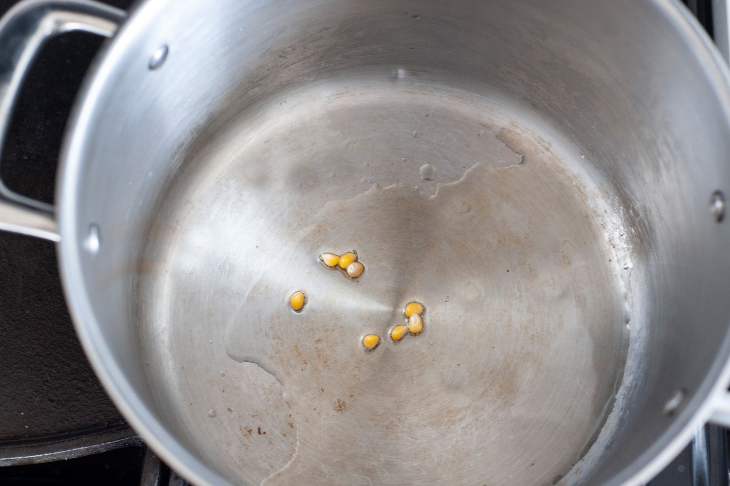 A few kernels of corn in oil in a big pot to make easy kettle corn.