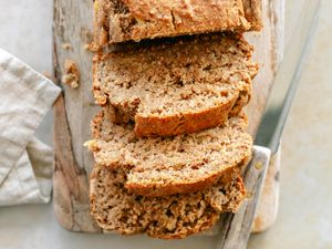 Sliced banana bread on a wooden board with a knife placed beside it