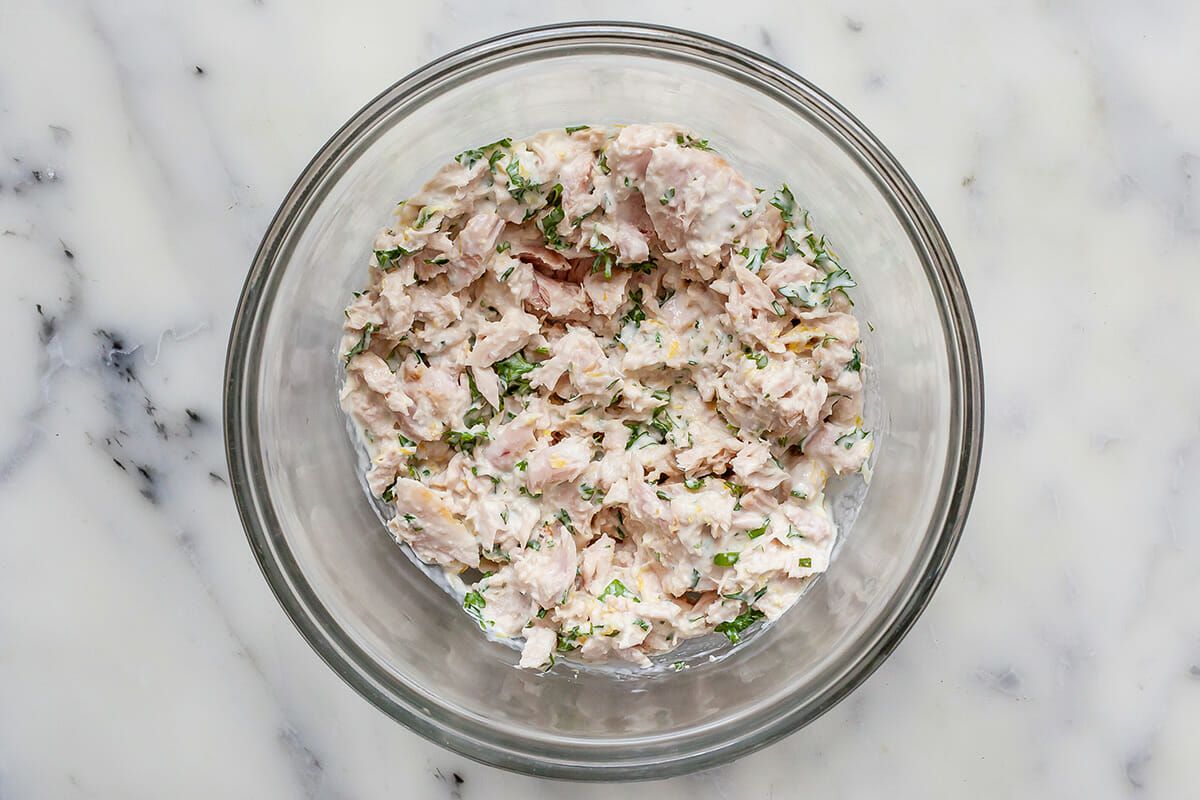 Tuna melt filling in a glass bowl on a marble countertop.