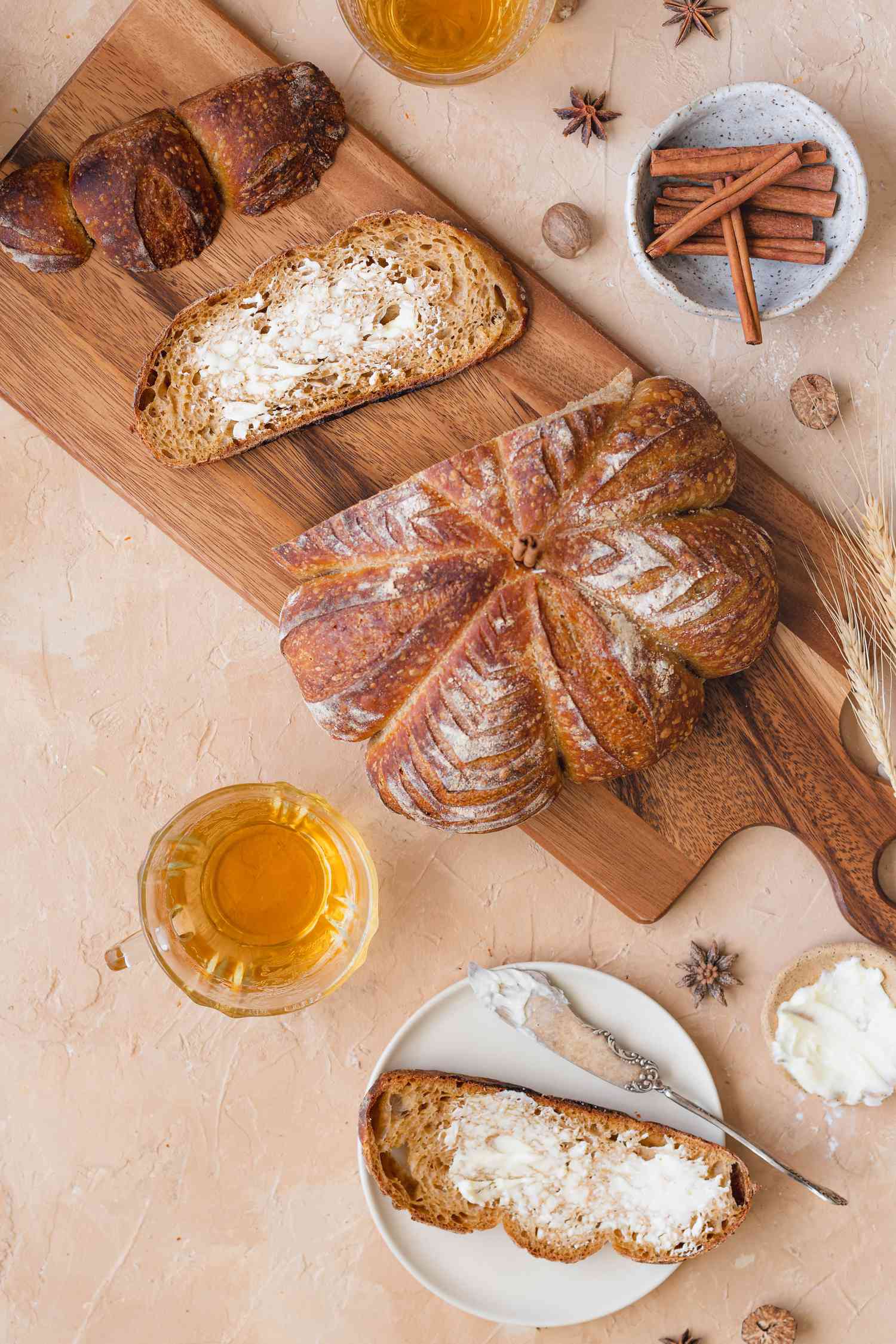 Overhead view of pumpkin-shaped sourdough loaf on a cutting board and with a slice cut off and buttered. 