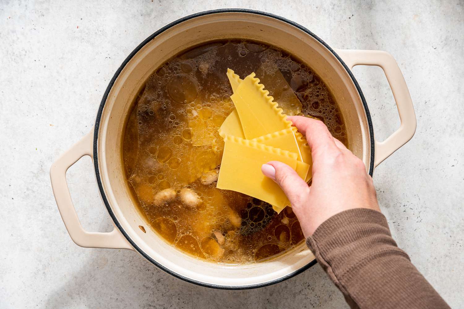 broken lasagna noodles added to dutch oven with the soup base white chicken lasagna soup recipe
