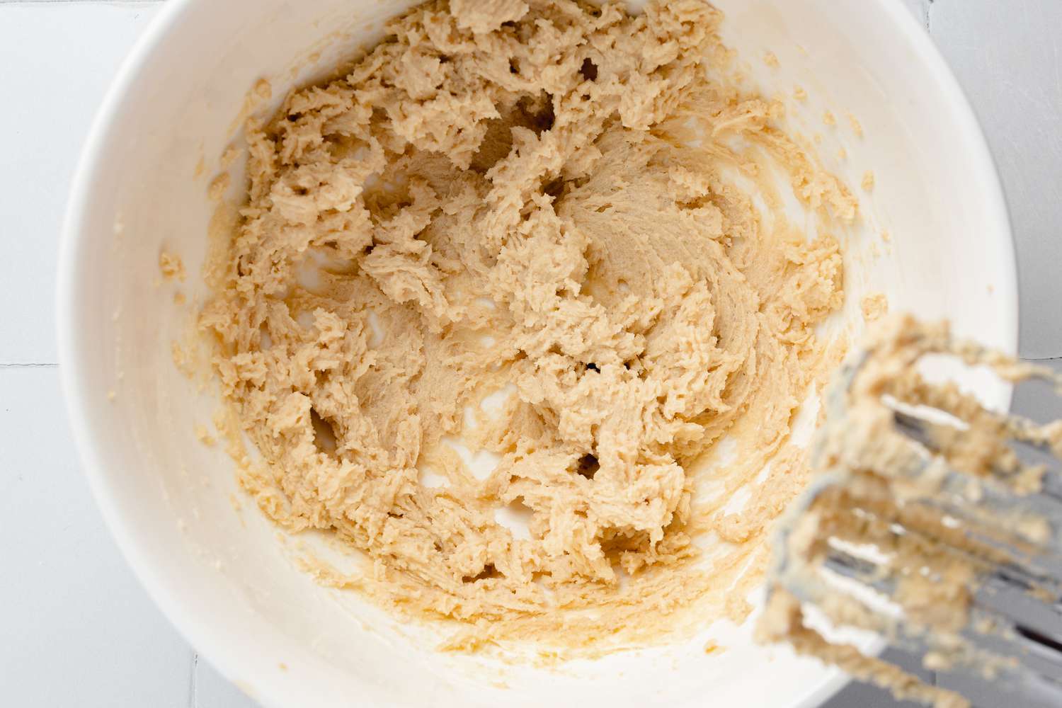 Sugars, Butter, and Vanilla Extract Whisked Together Using a Hand Held Mixer for Pecan Turtle Cookie Cup Recipe