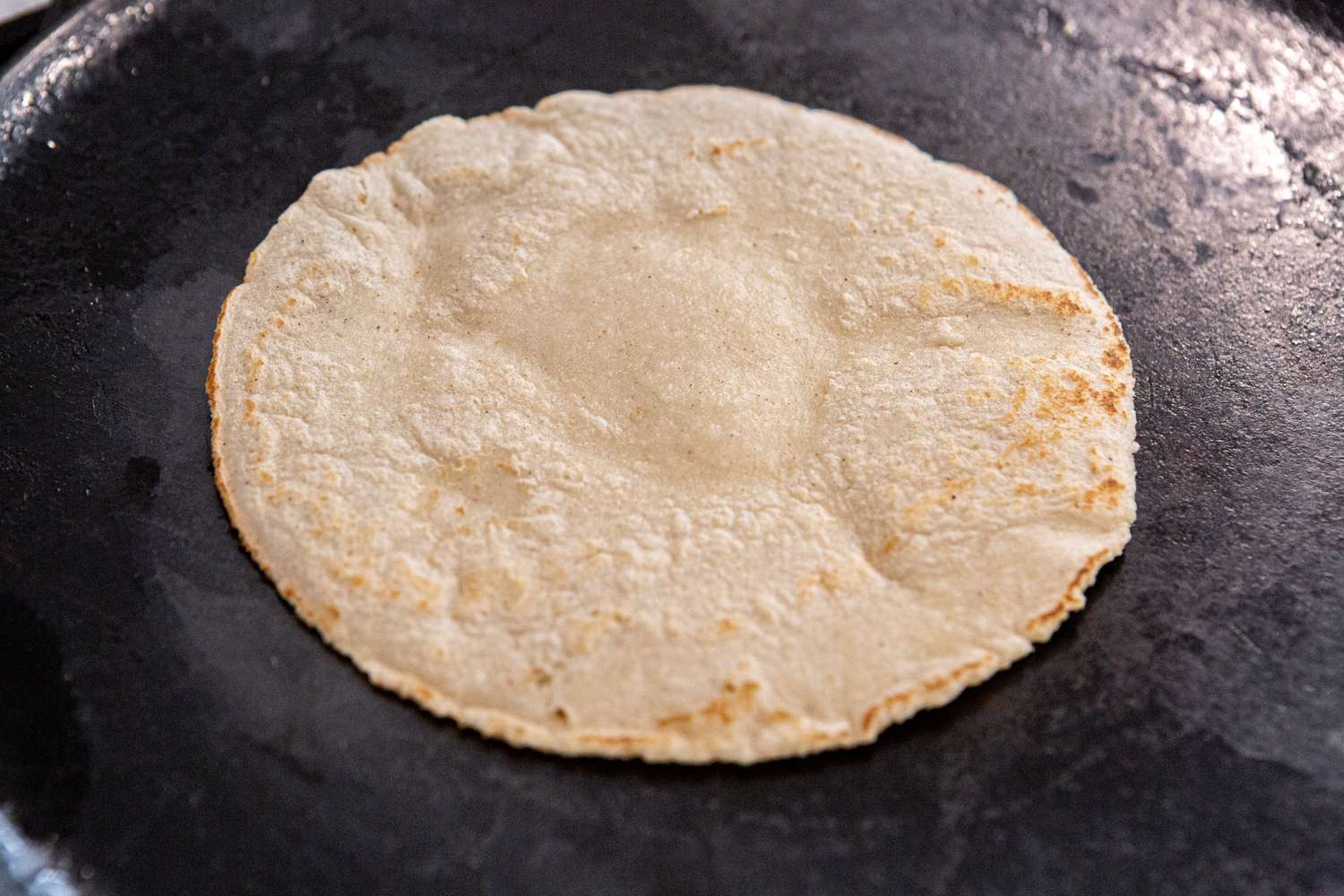 Frying a corn tortilla on a skillet 