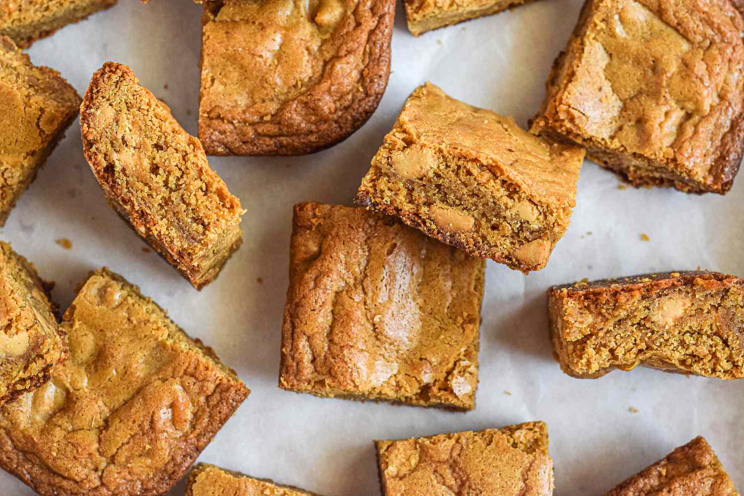 Overhead view of blonde brownies scattered on a counter with a butter knife next to it