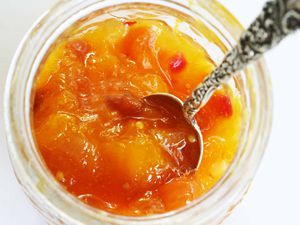 Overhead view of an open jar of mango chutney with a spoon in it