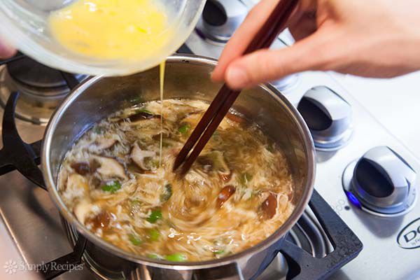 Stirring in beaten eggs in egg drop soup with chop sticks 