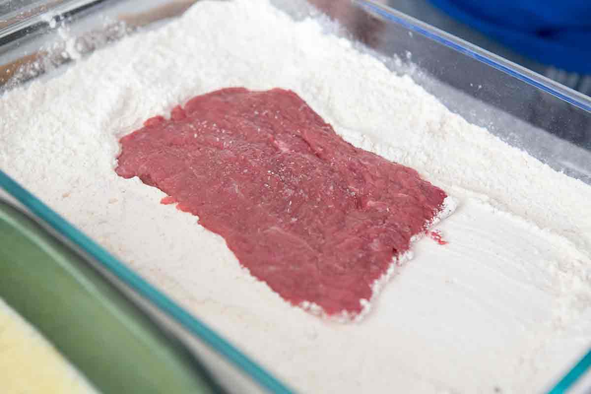 Dredging sirloin in flour in a baking dish