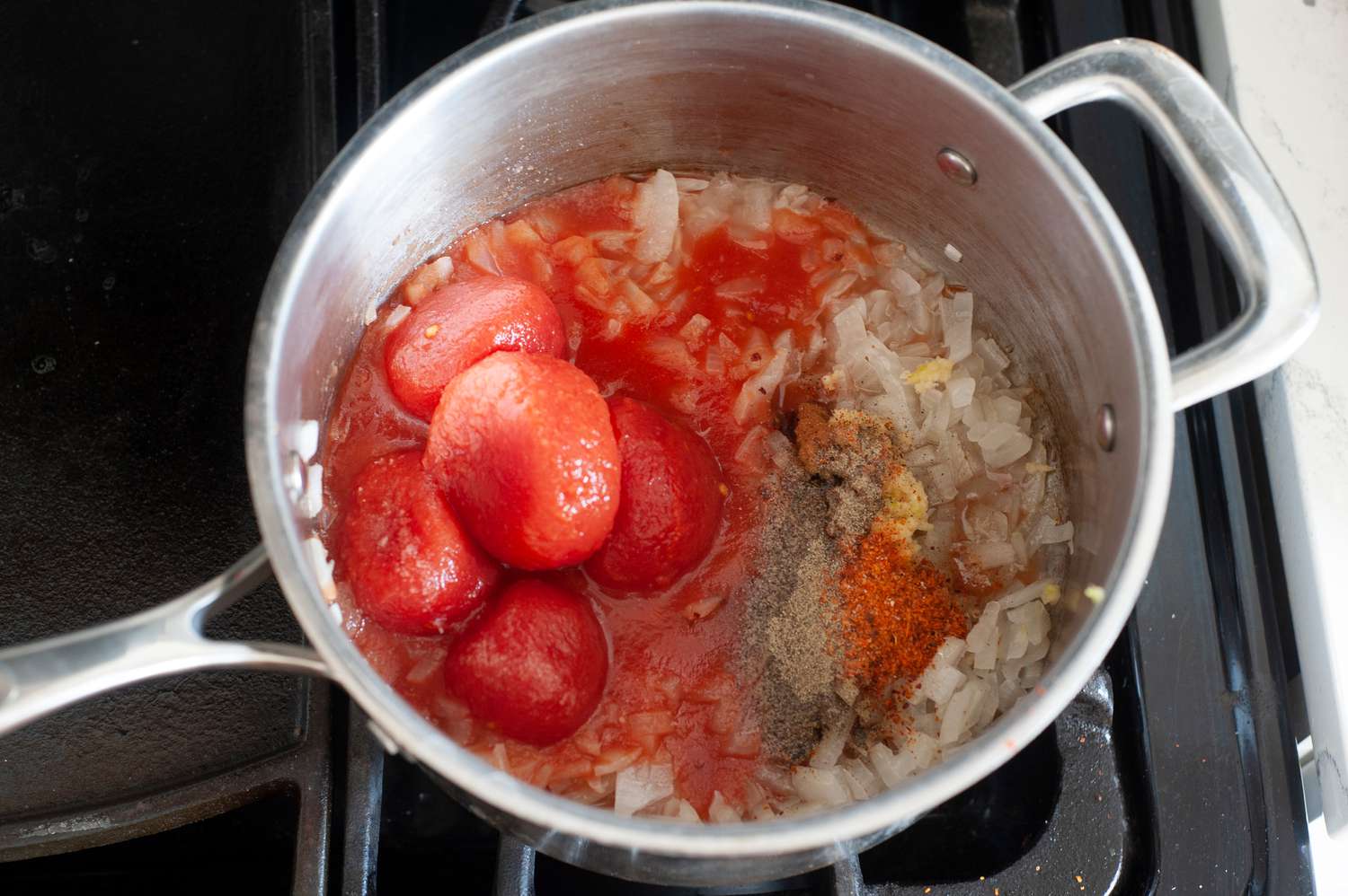 Onions and canned tomatoes cooking in a pot to make Turkish-style braised green beans.