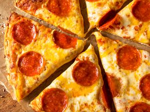 Slices of cooked frozen pepperoni pizza arranged on a wooden surface