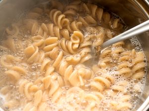 Pasta cooking in a pot with a utensil stirring it
