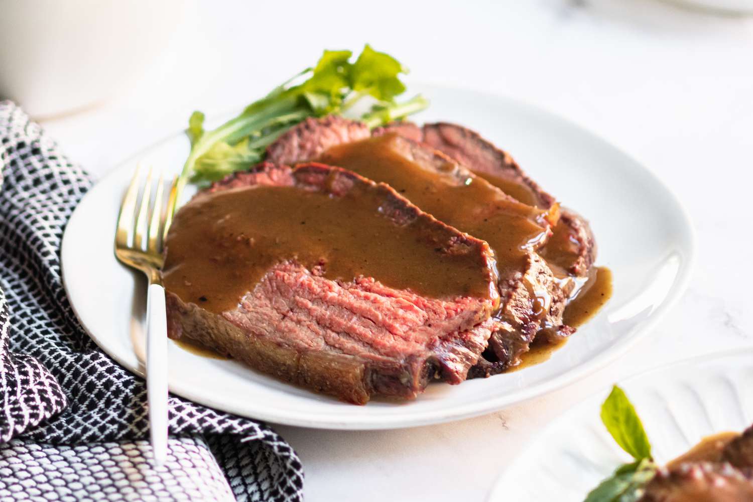 A plate of rump roast sliced and topped with gravy on a plate