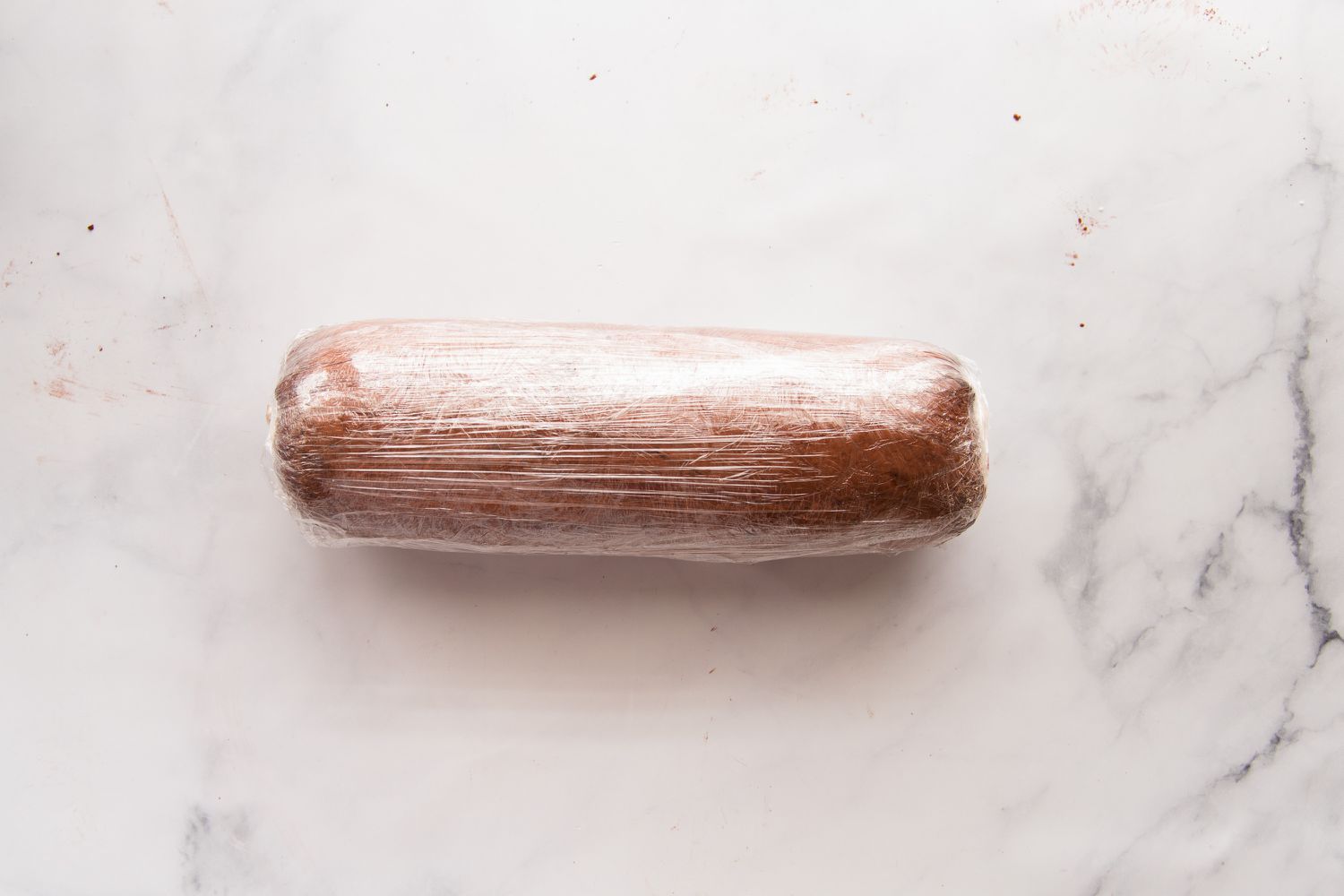 Chocolate swiss roll wrapped in plastic wrap.