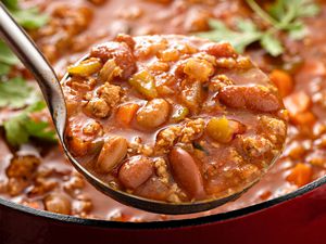 ladle of chili hovering over a pot of chili