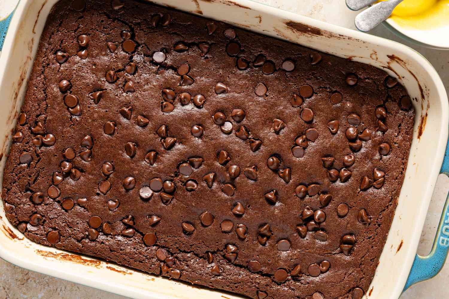 Overhead view of a baking dish of baked batter for Chocolate Dump Cake recipe on a tan countertop