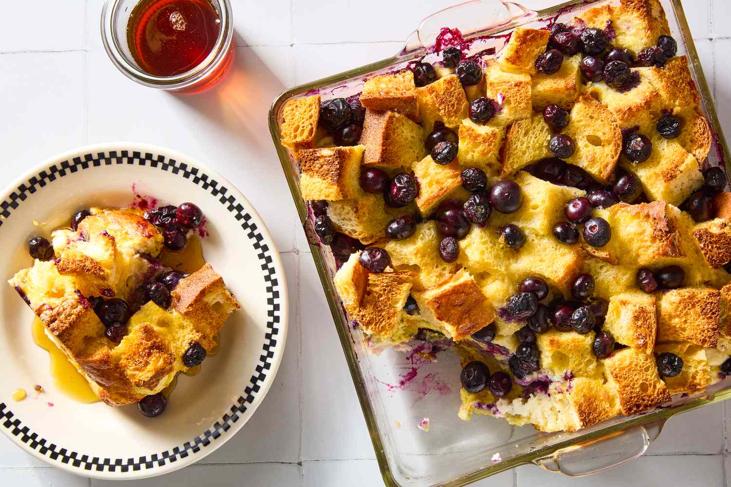 Blueberry maple breakfast bake in a casserole dish, alongside plated portion drenched in maple syrup
