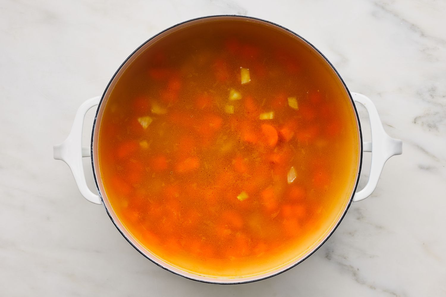 Carrots, chickpeas, and broth added to Dutch oven for hummus soup recipe