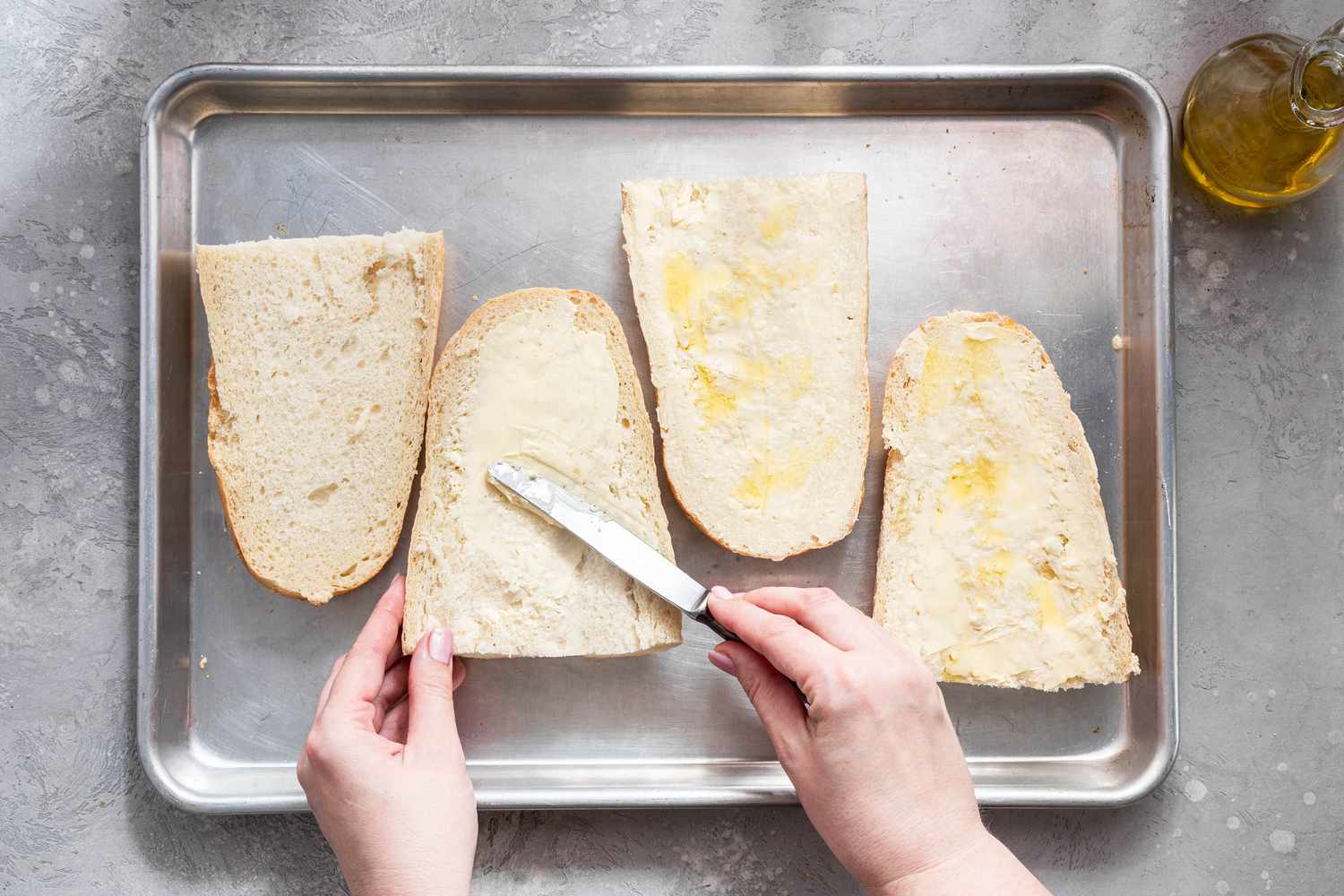 Butter and Olive Oil Spread Onto the French Bread Quarters on a Baking Sheet
