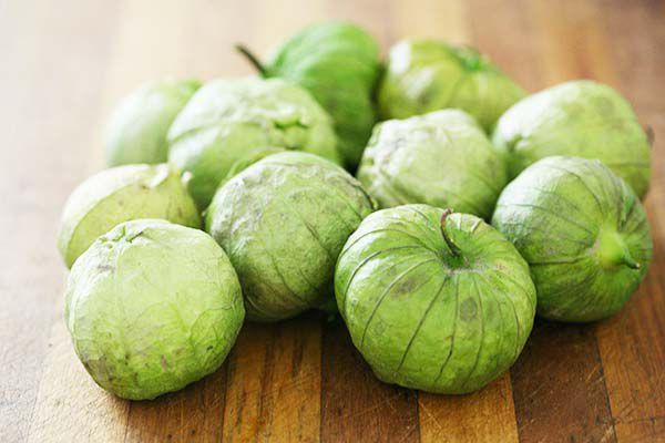 A group of green tomatillos on a wooden surface