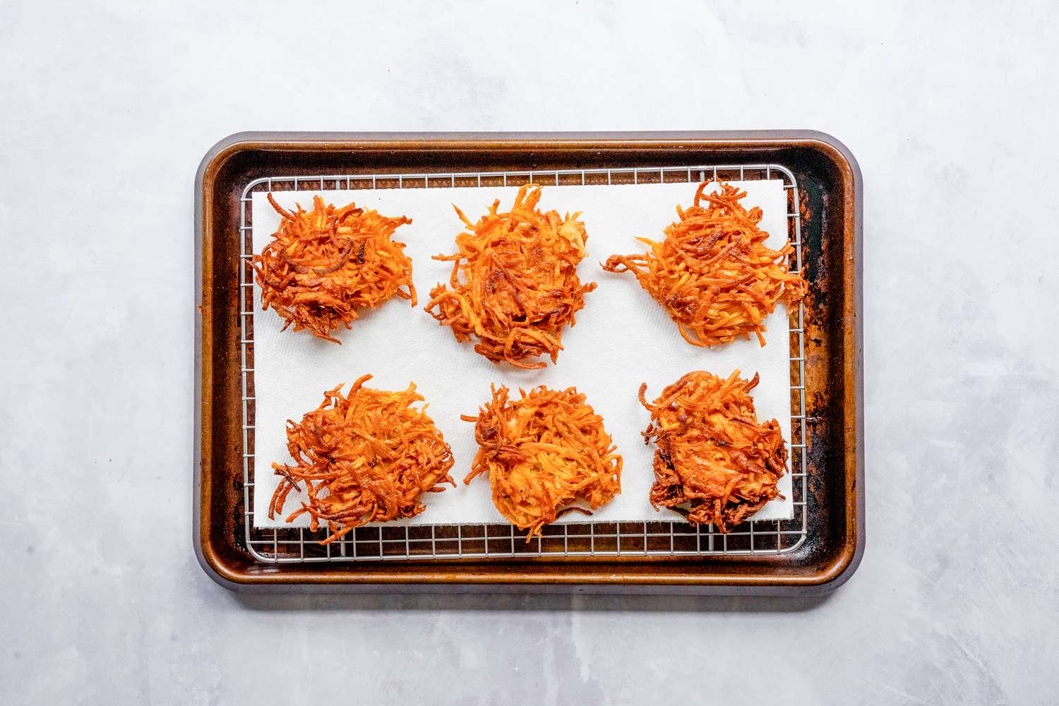 Sweet Potato Latkes on a Paper Towel Covered Wire Rack on a Baking Pan