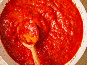 Tomato sauce cooking in a pan with a wooden spoon