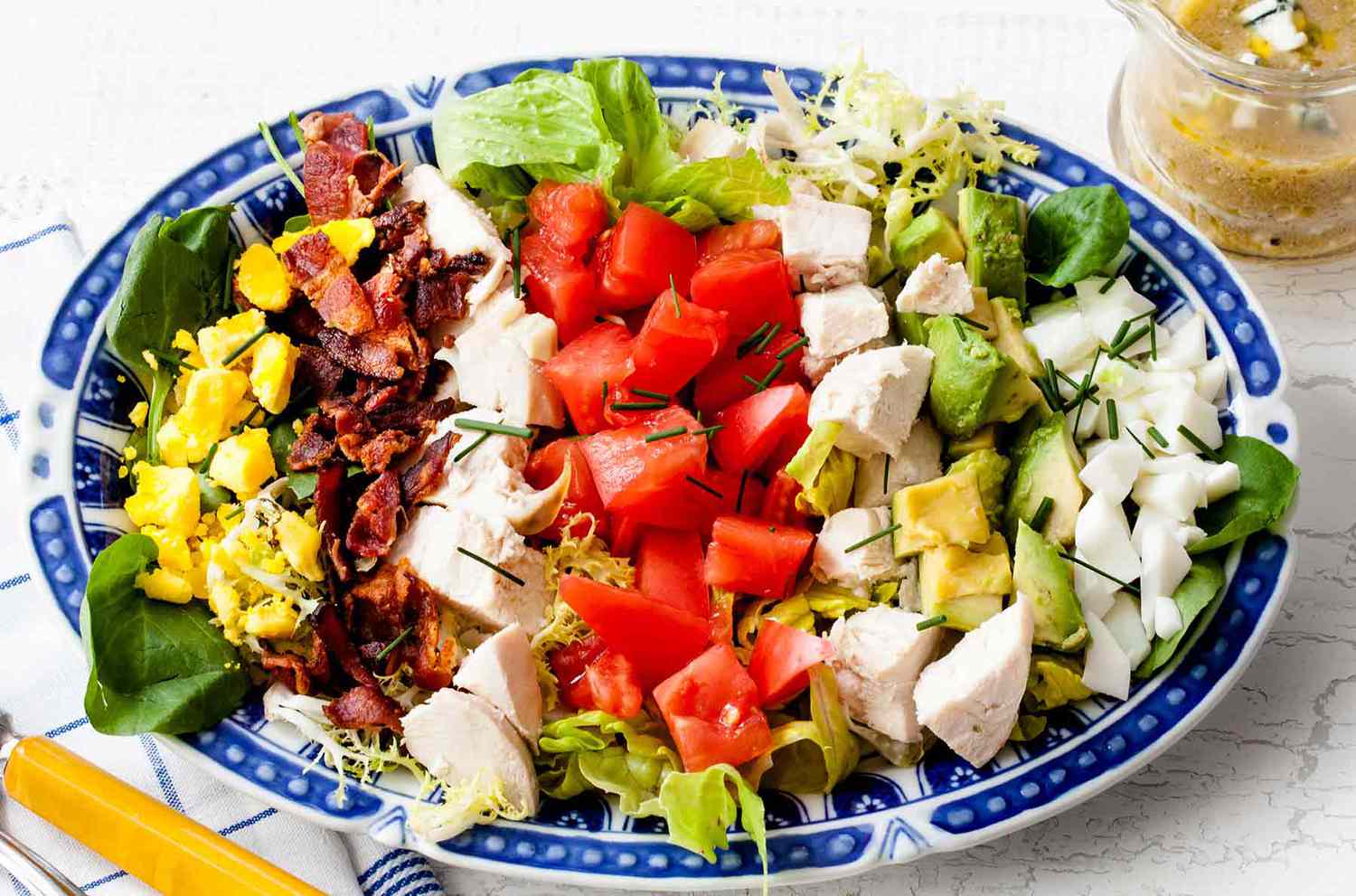 Cobb salad with greens, egg, bacon, chicken tomatoes on a plate