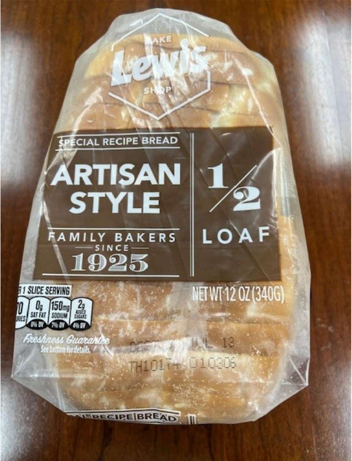 Packaged half loaf of Lewis artisanstyle bread on a wooden surface