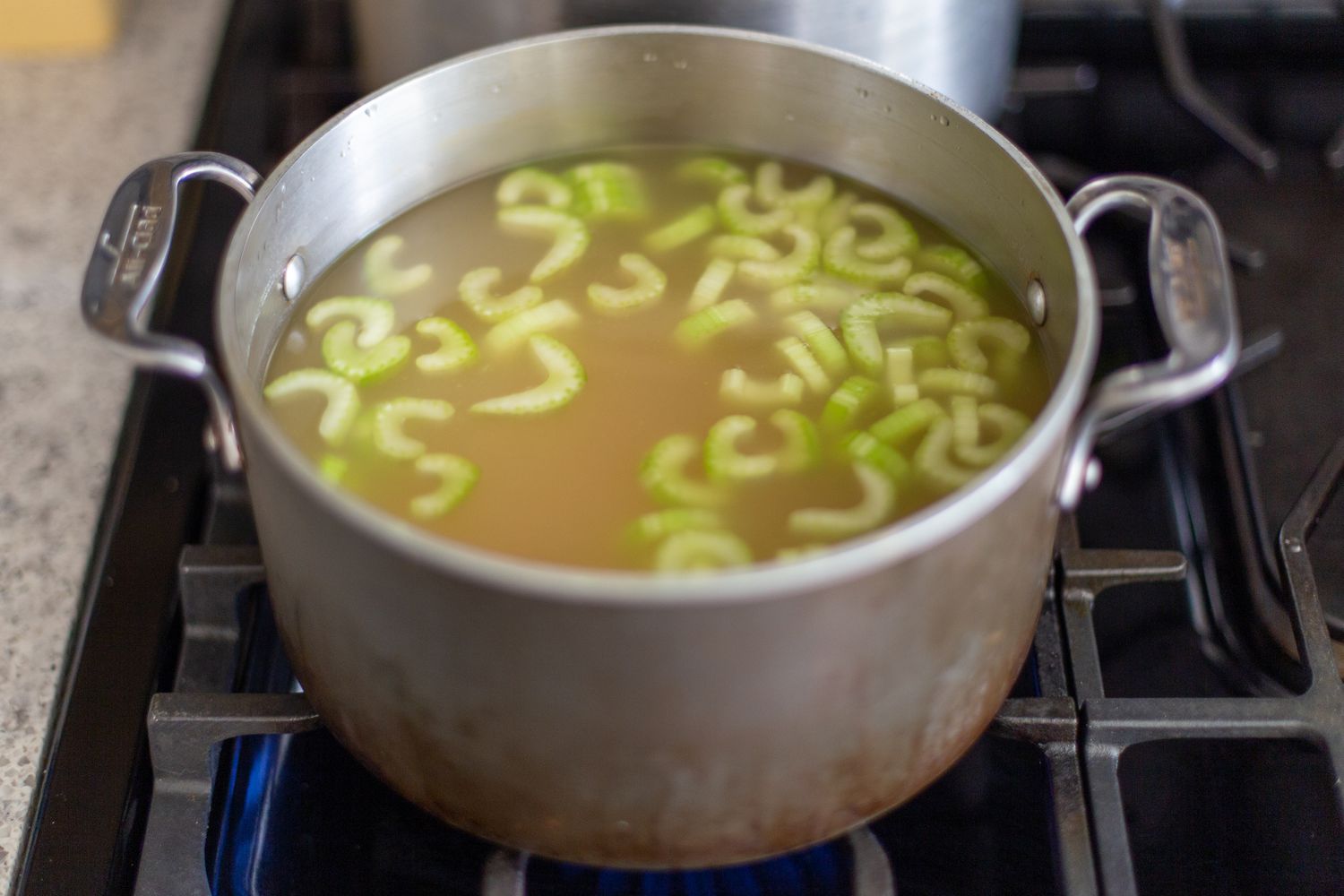 Simmering celery in chicken broth for easy beef kreplach recipe 
