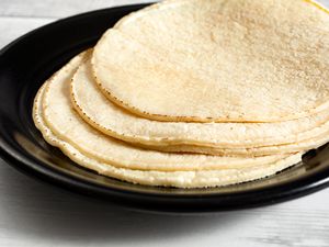 Side shot of a black plate plate with fresh corn tortillas