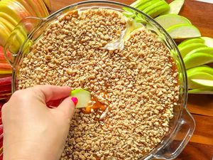 Hand scooping caramel apple dip with sliced apple