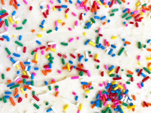 A close-up view of a white frosted cake decorated with colorful sprinkles