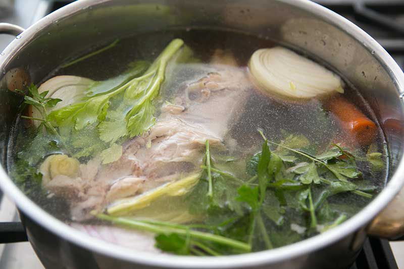Chicken stock carcass and vegetables with water in a stock pot