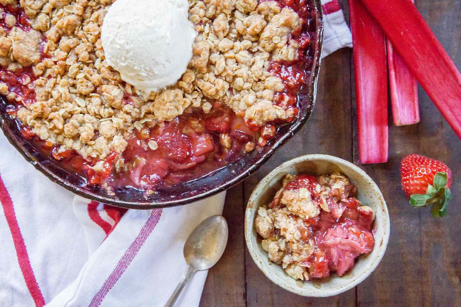 strawberry rhubarb crisp in a skillet with a portion removed and on a plate