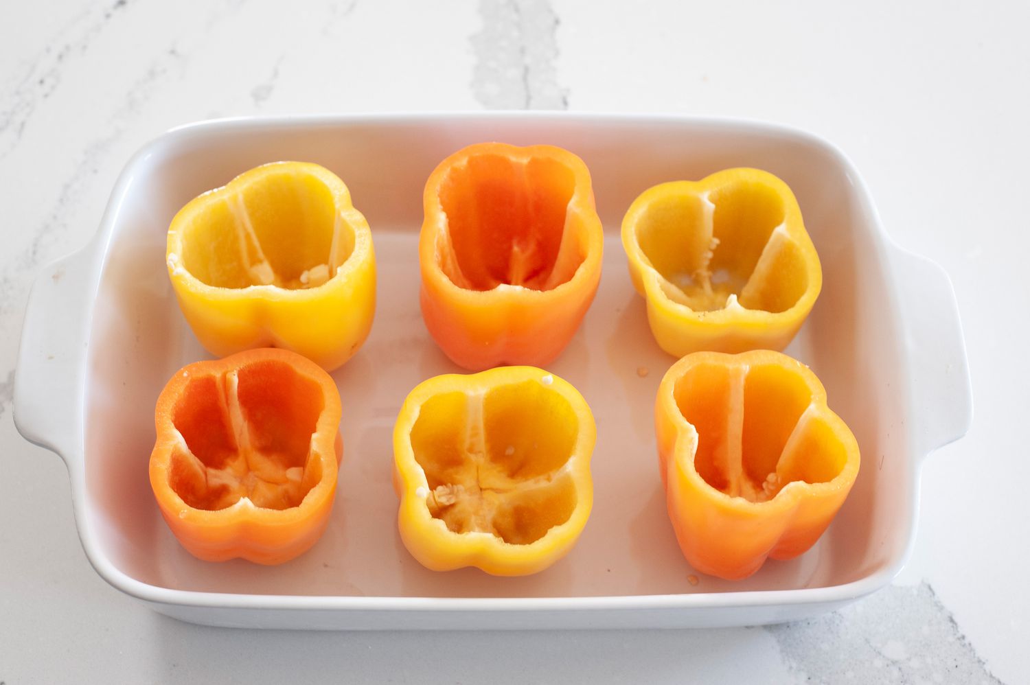 Bell peppers in a casserole dish for stuffed peppers with rice, tofu, and mushrooms
