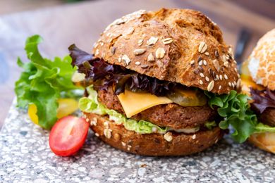 A whole grain bun sandwich with lettuce, cheese, and a patty on a surface