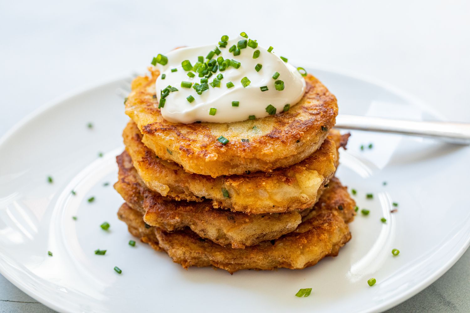 Leftover mashed potato pancakes on a plate and topped with sour cream and chives