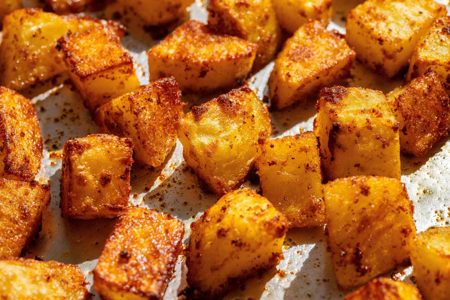 Spiced roasted potato cubes on a baking sheet, close-up view